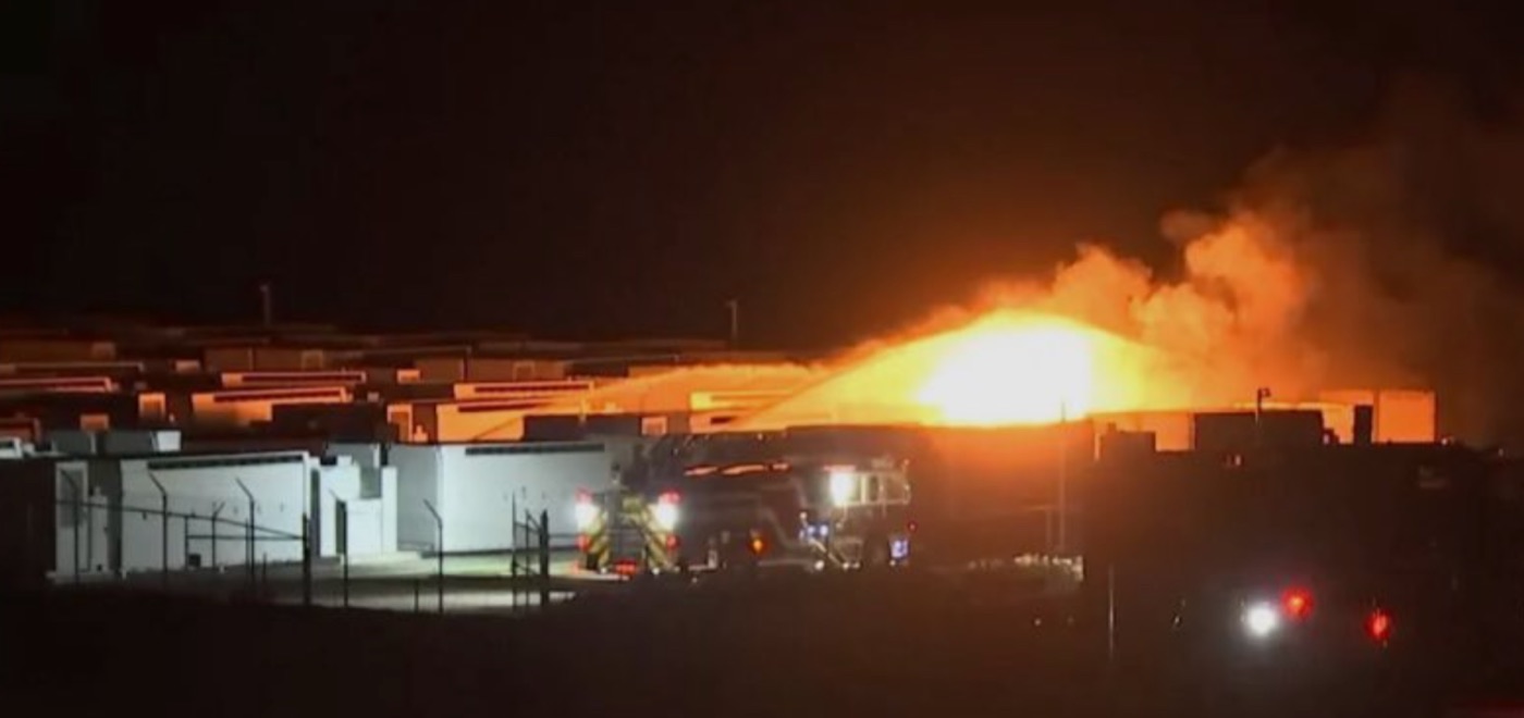 A massive fireball at night at the Boulder City, Nevada Tesla Megapack fire, with a fire engine parked in the foreground.